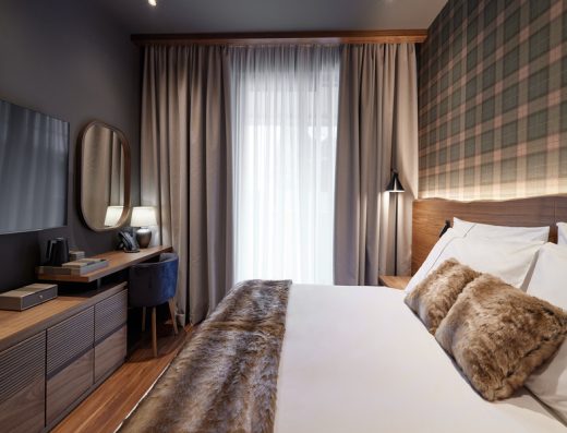 Hotelska soba u BOR Hotel by Karisma sa bračnim krevetom, krznenim prekrivačem i jastucima, kariranim tapetima i drvenim nameštajem