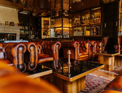 Cigar lounge u Event centar Kovačević sa braon Chesterfield kožnim sofama, barom sa kolekcijom viski boca i toplim ambijentalnim osvetljenjem