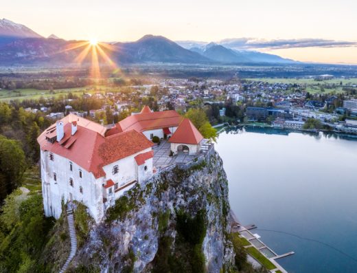 Aerial pogled na Bledski zamak na litici iznad jezera u blizini Festivalna dvorana Bled sa zalazkom sunca, planinama i panoramom grada
