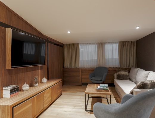 Dnevni boravak apartmana hotela Grand Kopaonik sa velikim TV ekranom na drvenoj zidnoj oblozi i udobnim kaučem