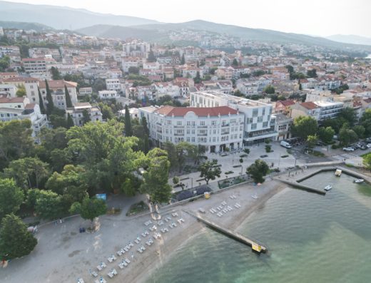 Aerial pogled na Hotel Miramare sa istorijskom i modernom zgradom, plažom sa ležaljkama, pristaništem, parkom, gradom i morem