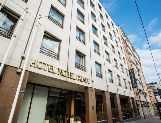 Fasada i ulaz u Hotel Nobel Palace sa zlatnim natpisom, belom kamenom fasadom i vertikalnim svetlećim znakom