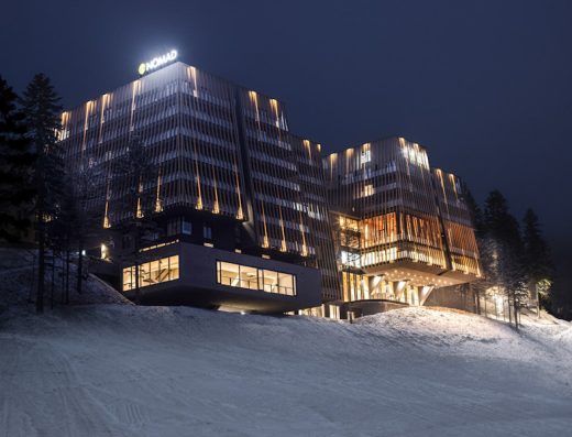 Eksterijer Hotel Nomad noću sa osvetljenom fasadom, drvenim lamelama i snežnim pejzažom