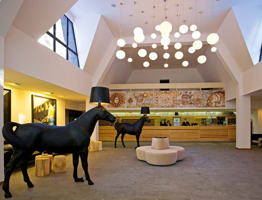 Lobi i recepcija u Hotel Palisad sa skulpturama konja, sferičnim lusterima, drvenim recepcijskim pultom i mozaičkim muralom na zidu