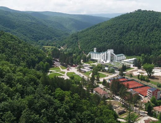 Aerial pogled na Hotel Planinka u dolini okruženoj zelenim šumama, sa kompleksom zgrada i teniskim terenima