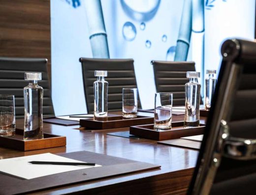 Detalj boardroom sale u Hotel Saint Ten sa kristalnim dekanterima, čašama, kožnim stolicama i bambusovom umetnošću u pozadini