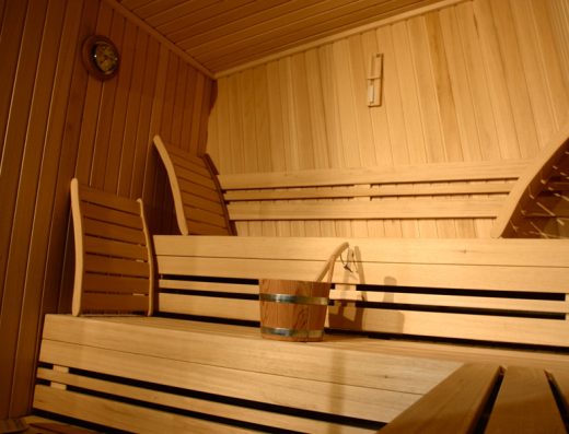 Finska sauna u Hotel Zira Beograd sa drvenim klupama od svetlog drveta, naslonima, drvenom kofom i satom na zidu
