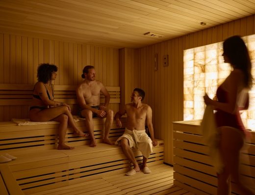 Finska sauna u Hotel Zlatibor Mona sa grupom gostiju na drvenim klupama, osvetljenim zidom od himalajske soli i toplim ambijentalnim osvetljenjem
