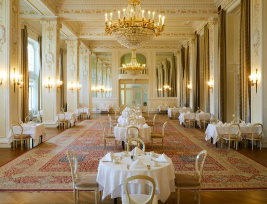 Balska dvorana u Kempinski Palace Portorož sa zlatnim kristalnim lusterima, belim stolnjacima, zlatnim stolicama, persijskim tepihom i klasičnim štuko dekoracijama