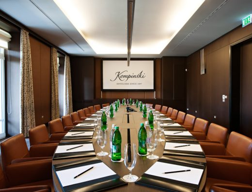 Boardroom sala u Kempinski Palace Portorož sa ovalnim stolom, braon kožnim stolicama, projektorskim platnom sa logom Kempinski i tamnim panelima