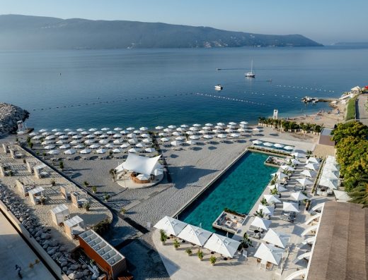 Aerijalni pogled na beach club Lazure Hotel & Marina sa bazenom, plažom, suncobranima, tirkiznim morem i planinama