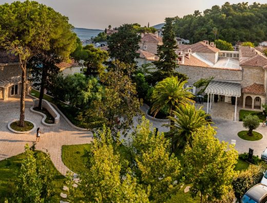 Aerijalni pogled na dvorište Lazure Hotel & Marina sa kamenom fasadom, zelenim vrtom, palmama, borovima i zalaskom sunca