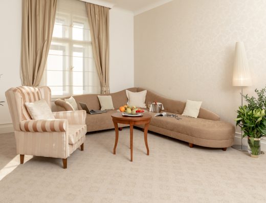 Dnevni boravak apartmana u Le Premier Boutique Hotel sa bež kaučem, prugastom foteljom, okruglim stolićem, voćnim tanjirom i podnom lampom
