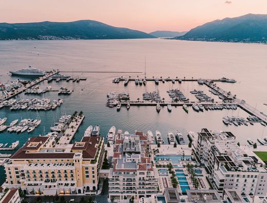 Aerial pogled na Regent Porto Montenegro i marinu u zalazak sunca sa žutom fasadom hotela, bazenima, jahtama i Bokokokotorskim zalivom