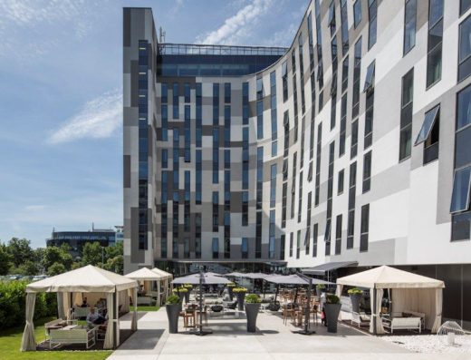 Eksterijer hotela Zijin Hotel Belgrade sa modernom sivom geometrijskom fasadom, terasom sa suncobranima, kabanama i zelenim travnjakom