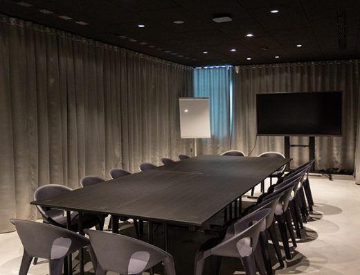 Boardroom sala u hotelu Zonar Zagreb sa tamnim stolom za dvanaest osoba, sivim dizajnerskim stolicama, zavesama i televizorom iz vertikalnog ugla